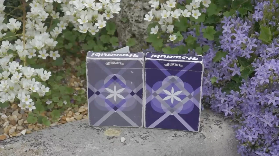 Purple and grey Wistaria tuck boxes photographed among flowers.